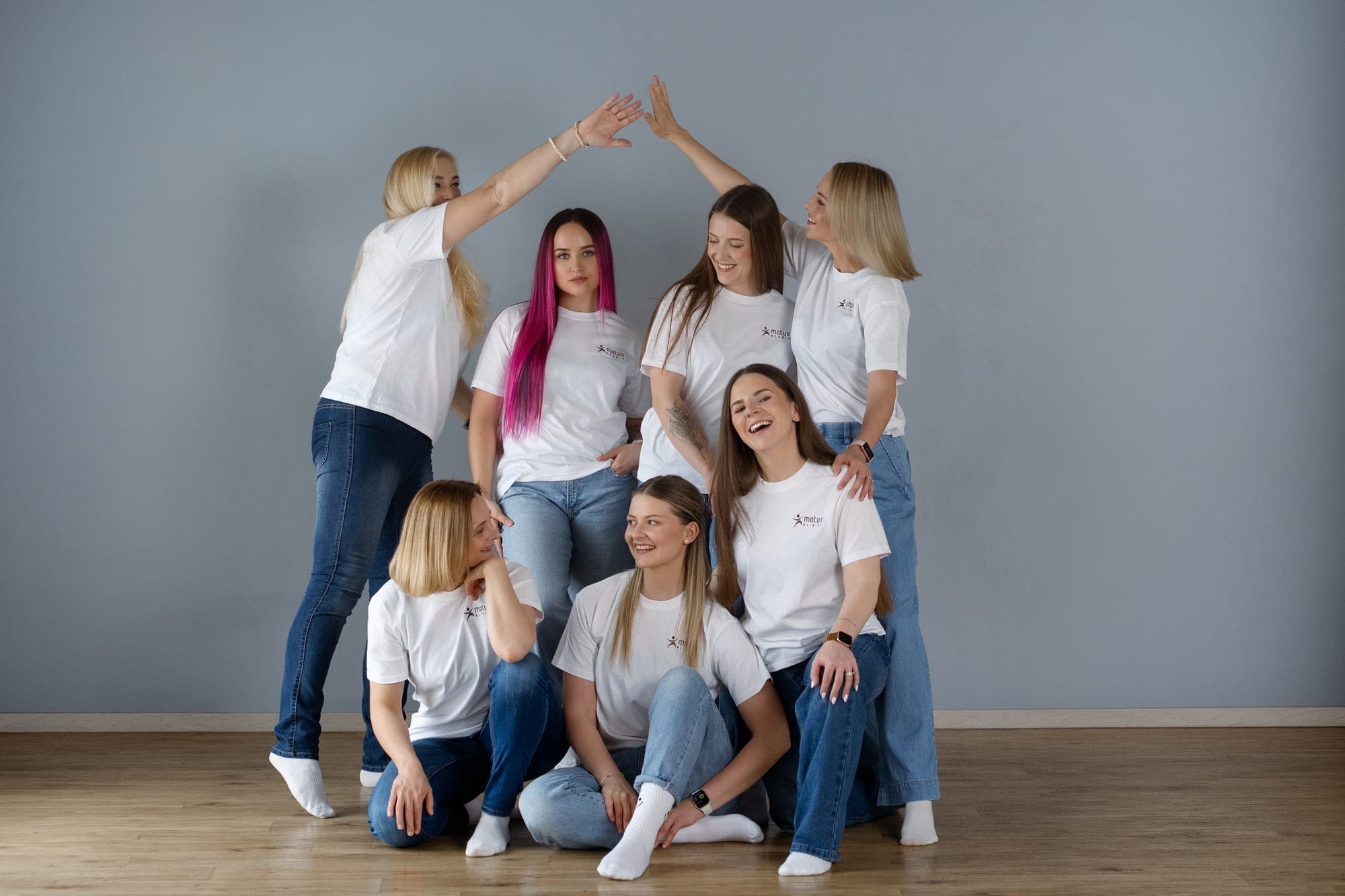Motus komanda juokiasi susispietusi prie studijos sienos